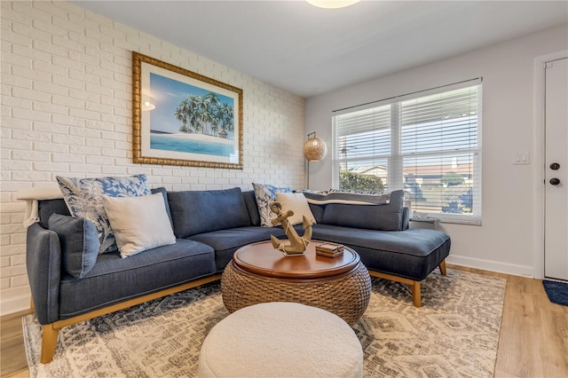 living room with brick wall and light hardwood / wood-style floors