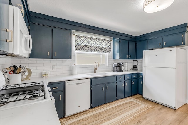 kitchen with white appliances, blue cabinets, sink, light hardwood / wood-style flooring, and backsplash