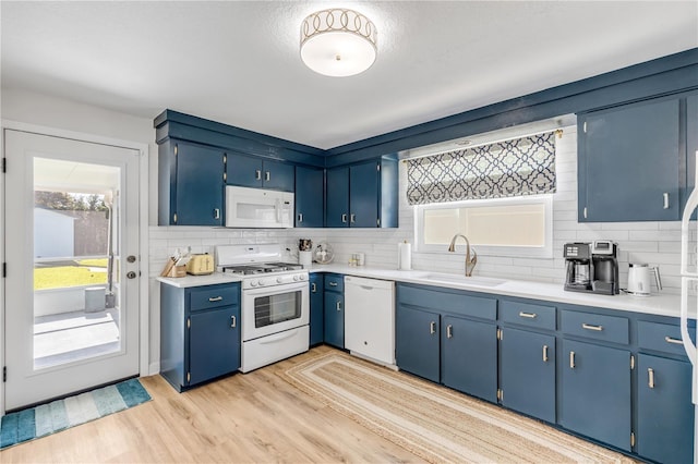 kitchen with backsplash, white appliances, blue cabinets, light hardwood / wood-style floors, and sink