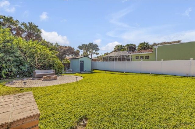 view of yard with glass enclosure, a fire pit, a storage shed, and a patio area