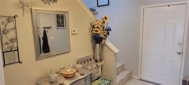 tiled entrance foyer with stairs and baseboards