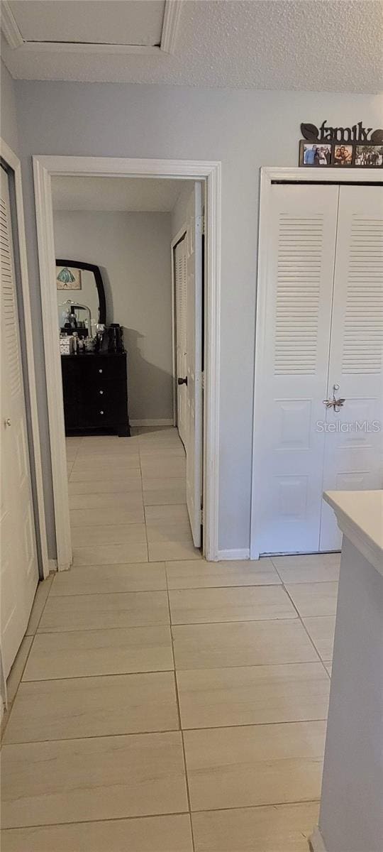 hallway with a textured ceiling and light tile flooring