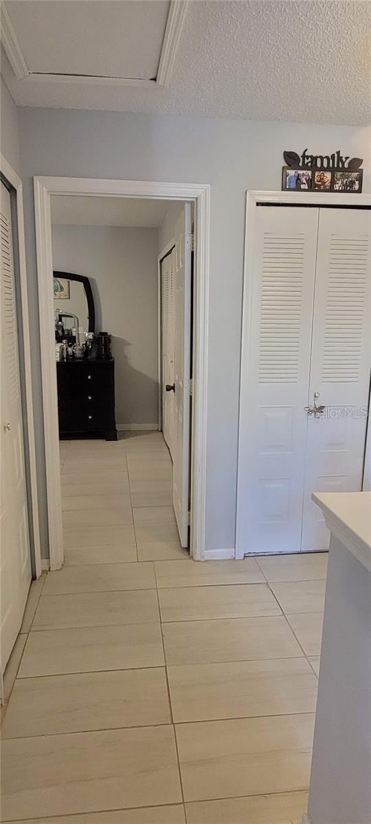 hallway featuring a textured ceiling and light tile patterned floors