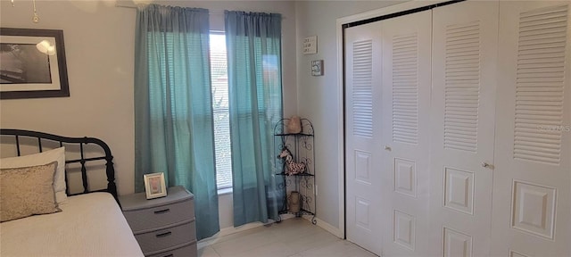 bedroom with light tile patterned floors, a closet, and baseboards