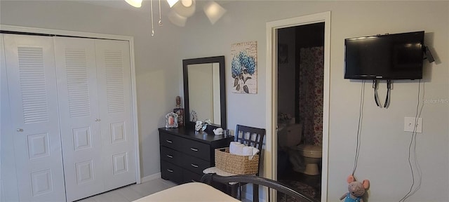 bedroom with connected bathroom, light tile flooring, and a closet