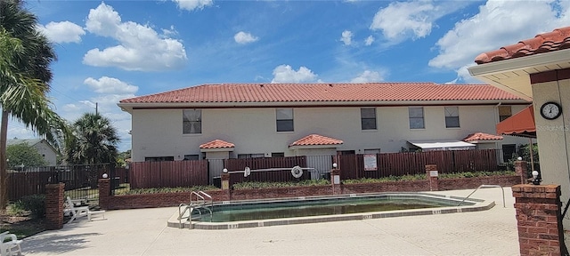 rear view of house with a tiled roof, a patio, and fence