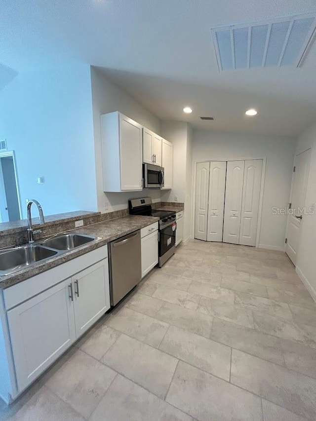 kitchen with stainless steel appliances, white cabinetry, and sink