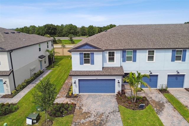 multi unit property with a garage, a shingled roof, decorative driveway, stucco siding, and a front lawn