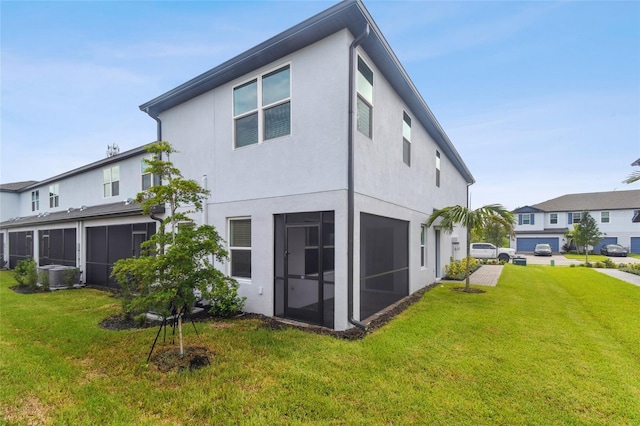 rear view of property with a sunroom, central AC unit, stucco siding, and a yard