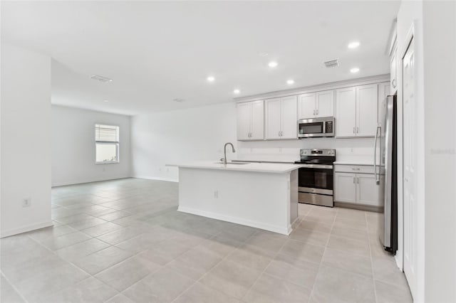 kitchen featuring stainless steel appliances, light countertops, visible vents, open floor plan, and a sink