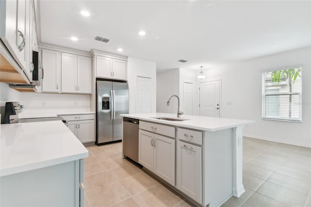 kitchen with stainless steel appliances, light countertops, visible vents, a kitchen island with sink, and a sink