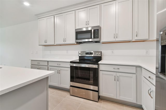 kitchen with light tile patterned floors, gray cabinets, stainless steel appliances, and light countertops