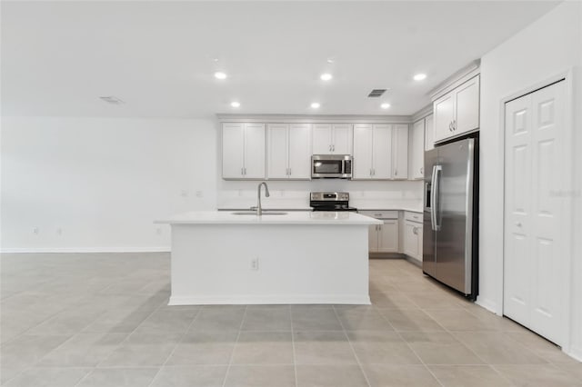 kitchen featuring a center island with sink, visible vents, appliances with stainless steel finishes, light countertops, and a sink