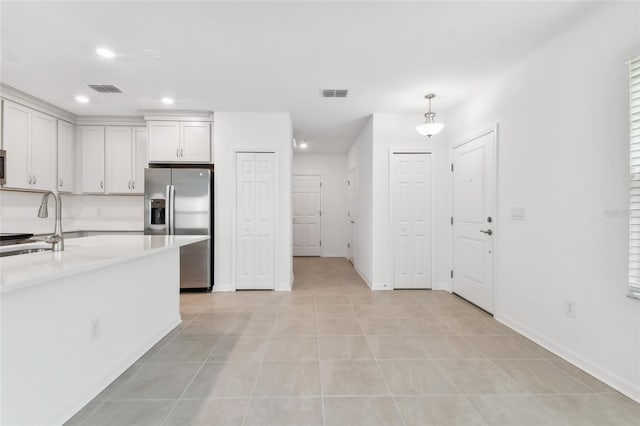 kitchen featuring light countertops, stainless steel refrigerator with ice dispenser, a sink, and visible vents