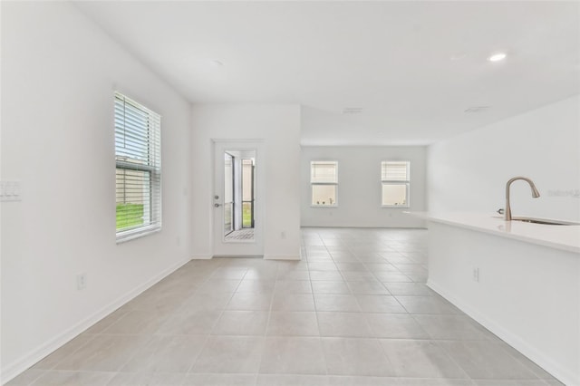 unfurnished room featuring a sink, baseboards, and light tile patterned floors