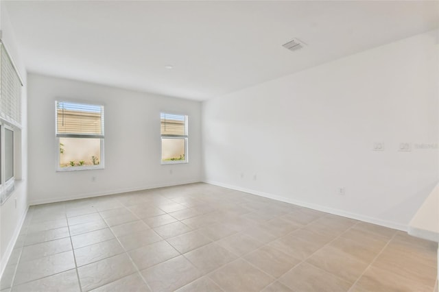 unfurnished room with light tile patterned flooring, visible vents, and baseboards