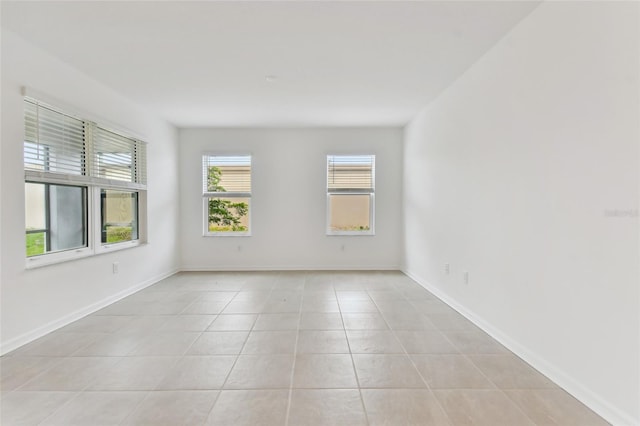 spare room with baseboards and light tile patterned flooring