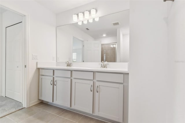 full bathroom featuring double vanity, visible vents, a sink, tile patterned flooring, and tiled shower