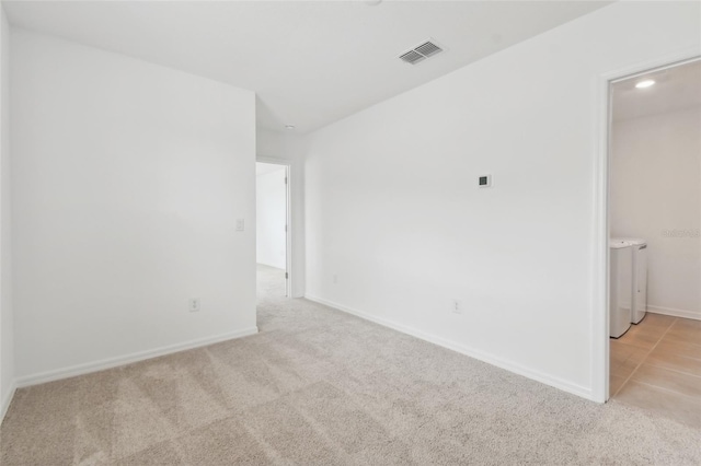 spare room with baseboards, visible vents, light colored carpet, and independent washer and dryer