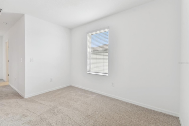 unfurnished room featuring baseboards and light colored carpet