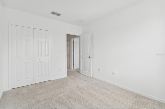 unfurnished bedroom featuring baseboards, a closet, visible vents, and carpet flooring