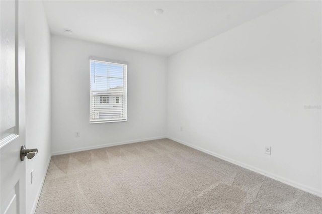 carpeted spare room featuring baseboards