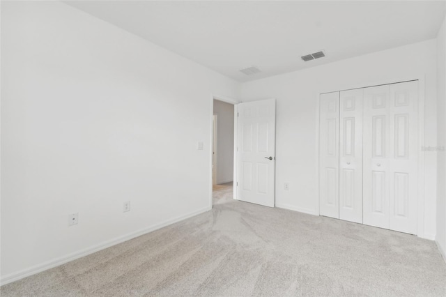 unfurnished bedroom with carpet, a closet, visible vents, and baseboards