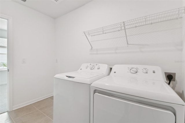 laundry area with light tile patterned floors, laundry area, washing machine and dryer, and baseboards