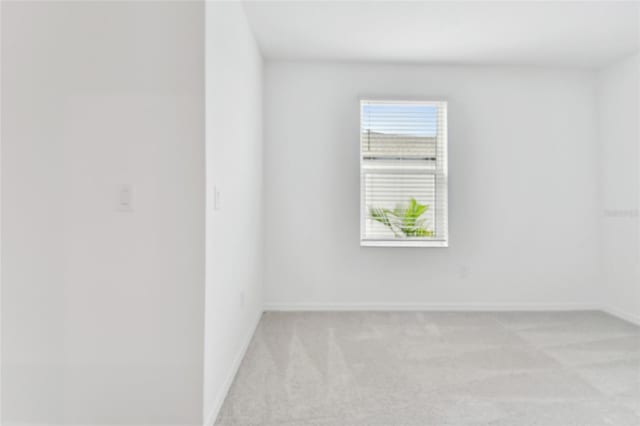 unfurnished room with light colored carpet and baseboards