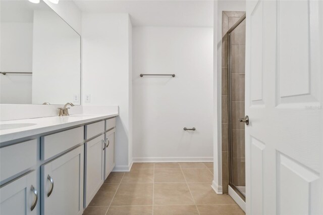 bathroom featuring double vanity, a stall shower, a sink, and tile patterned floors