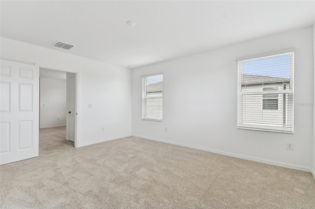 unfurnished room featuring light carpet, visible vents, and baseboards