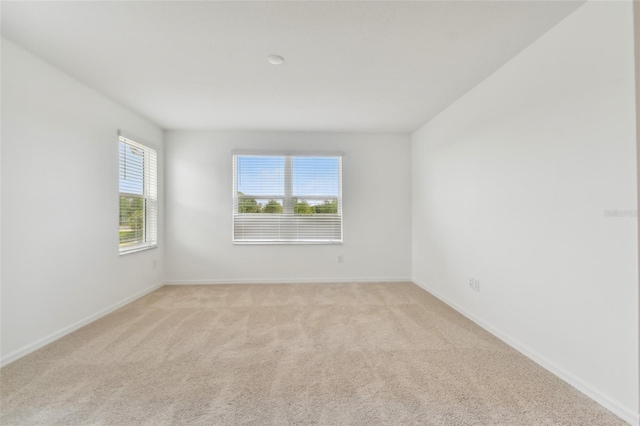 spare room featuring baseboards and light colored carpet