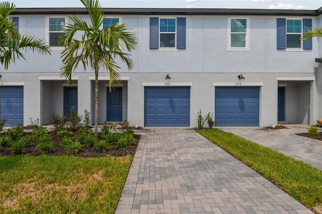 view of property featuring a garage, driveway, and stucco siding