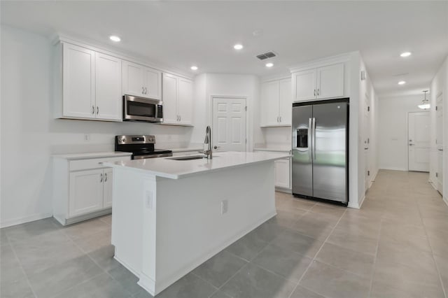 kitchen featuring stainless steel appliances, white cabinets, a center island with sink, sink, and light tile patterned flooring