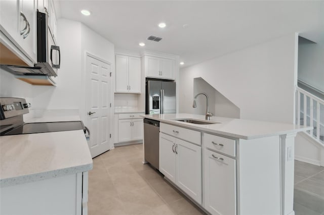 kitchen with a center island with sink, visible vents, stainless steel appliances, white cabinetry, and a sink