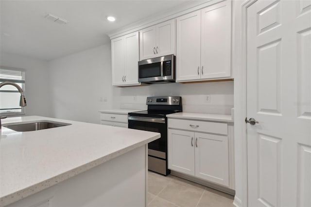 kitchen featuring stainless steel appliances, light tile patterned floors, light stone countertops, sink, and white cabinetry