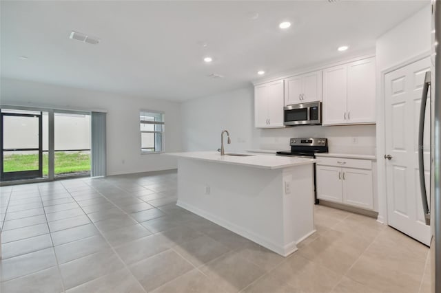 kitchen featuring light tile patterned flooring, white cabinets, a center island with sink, and stainless steel appliances