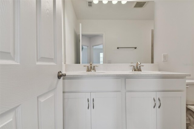 bathroom featuring dual bowl vanity and toilet