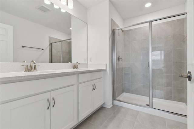 bathroom featuring a stall shower, tile patterned flooring, a sink, and visible vents