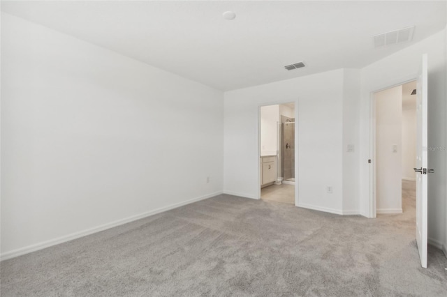 unfurnished bedroom featuring ensuite bathroom and light carpet