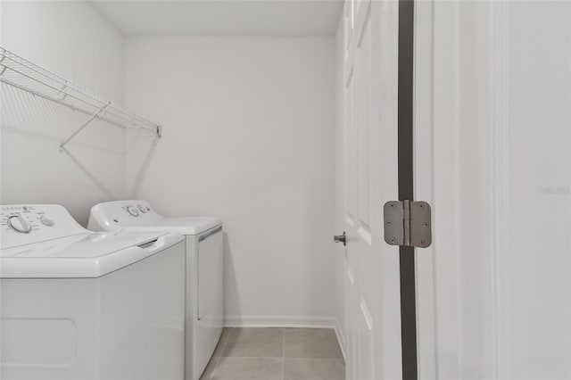 laundry area with laundry area, separate washer and dryer, light tile patterned flooring, and baseboards