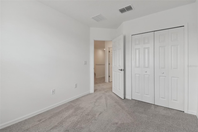 unfurnished bedroom featuring light carpet and a closet