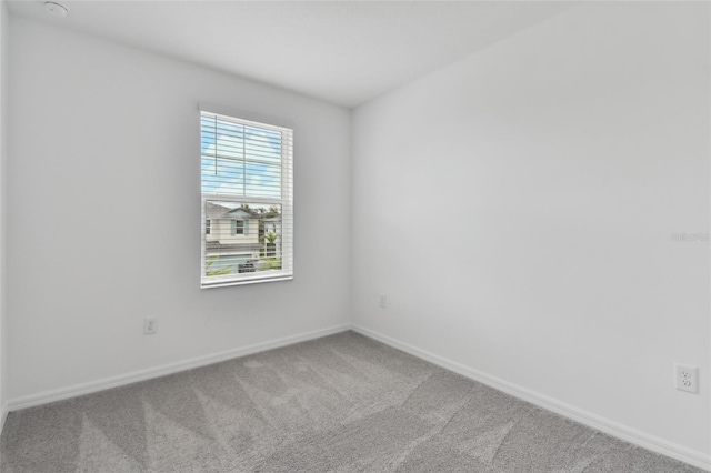 carpeted spare room featuring baseboards