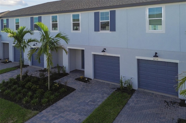 townhome / multi-family property featuring driveway, an attached garage, and stucco siding