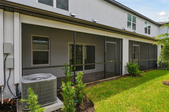 rear view of property featuring a lawn, a sunroom, and central AC unit