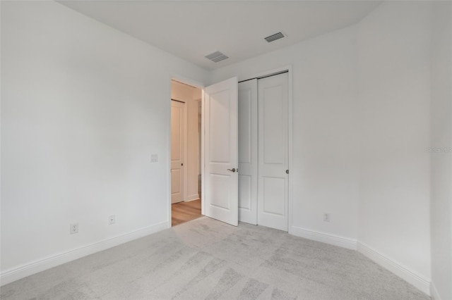 unfurnished bedroom with light carpet and a closet