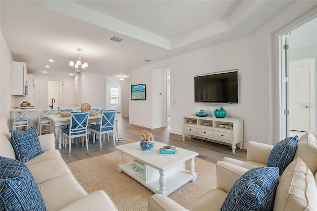 living room with visible vents, baseboards, an inviting chandelier, light wood-type flooring, and recessed lighting