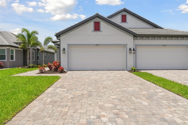 ranch-style home with stucco siding, a front lawn, decorative driveway, and a garage