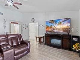 living room featuring ceiling fan, light hardwood / wood-style floors, and vaulted ceiling