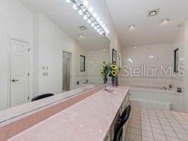 bathroom featuring tile patterned floors, a tub, vanity, and lofted ceiling